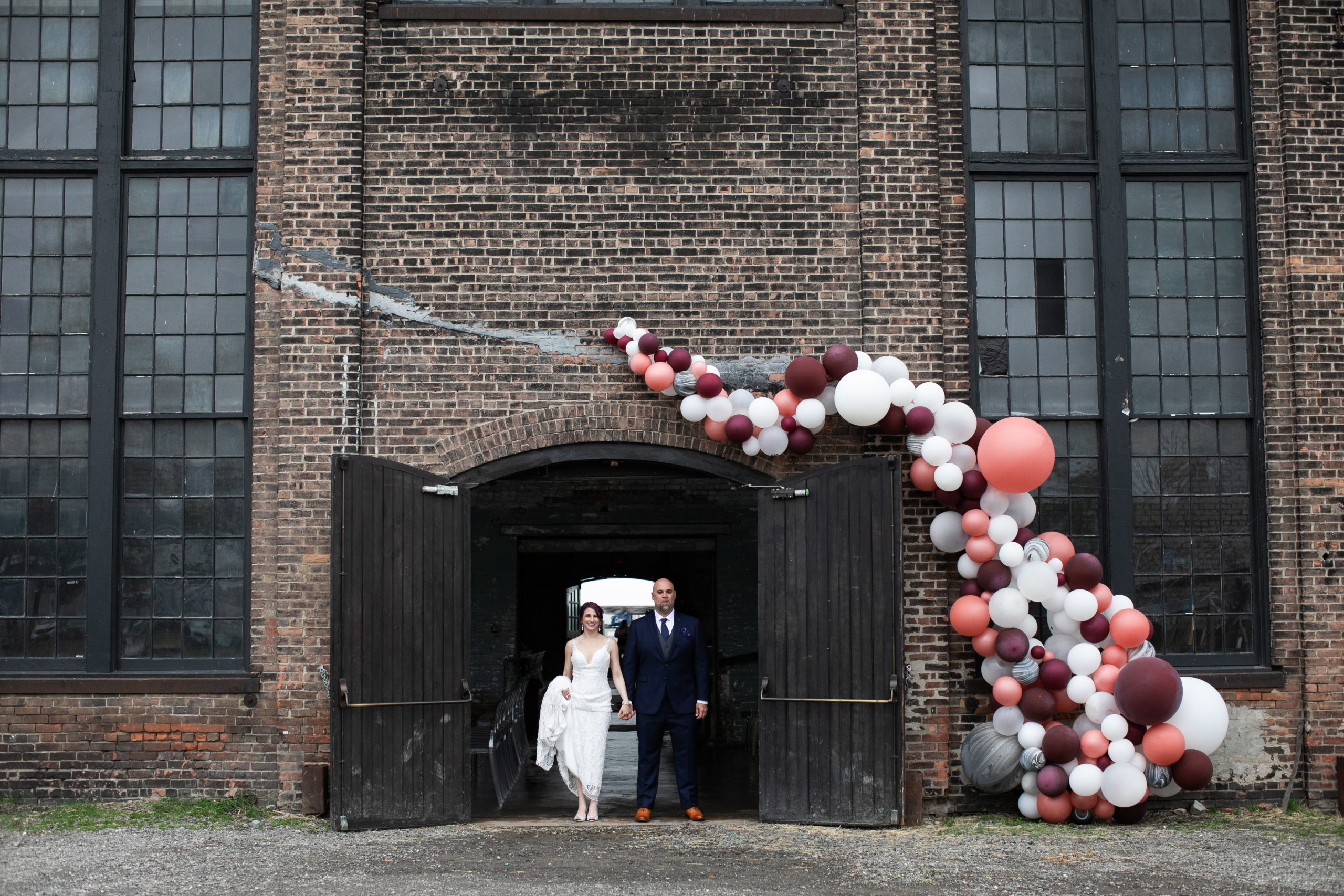 Couple posing in Basilica Hudson doorway with ballon arch